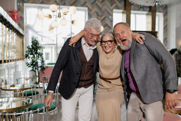 an older lady hugs 2 of her friends as tehy smile