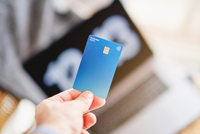 A woman holding a blue visa credit card for Essential Credit Union in Houston