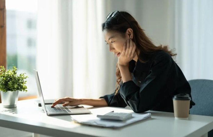 a woman looking at her personal savings account on Essential credit unions website on her laptop