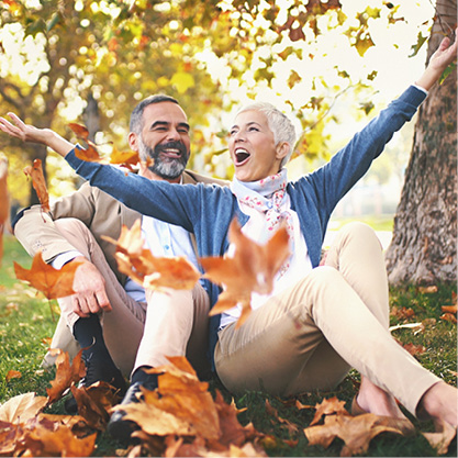 couple sitting in park surrounded by fall leaves