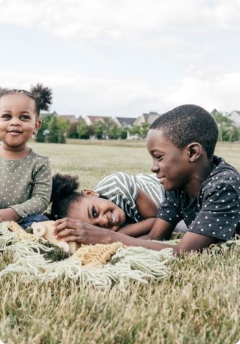 young kids lying on blanket outside on lawn in park